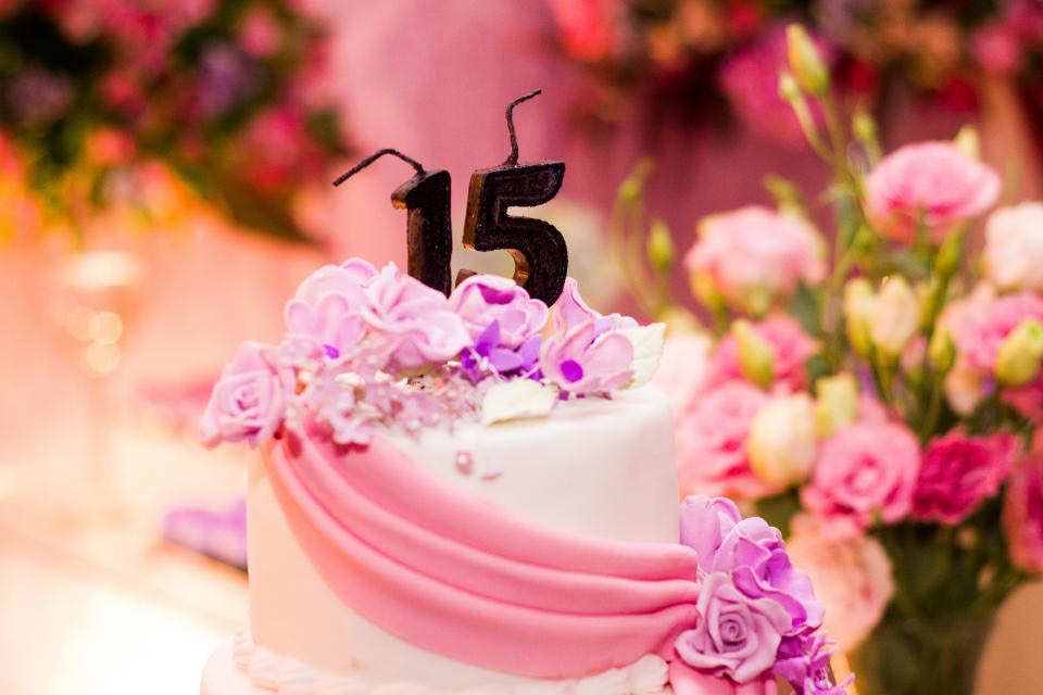 Bolo de 15 anos branco e rosa com velas no formato do número 15 e flores lilás