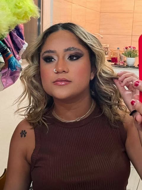 Cliente da H•LUX MAKEUP com olhos esfumados e cabelo ondulado, maquiagem finalizada.